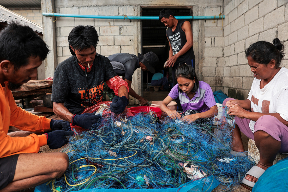 Members of the fishing community on Koh Haad Sai Dam Island remove crabs from a fishing net, in Ranong province, Thailand, May 20, 2026. REUTERS/Chalinee Thirasupa