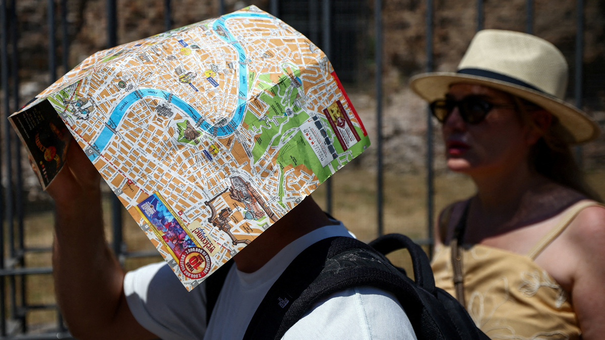 A tourist uses a map of Rome to shield their face from the sun beside the base of the Temple of Venus and Roma, opposite the Colosseum, during a heatwave in Rome, Italy, June 20, 2026. REUTERS/Guglielmo Mangiapane