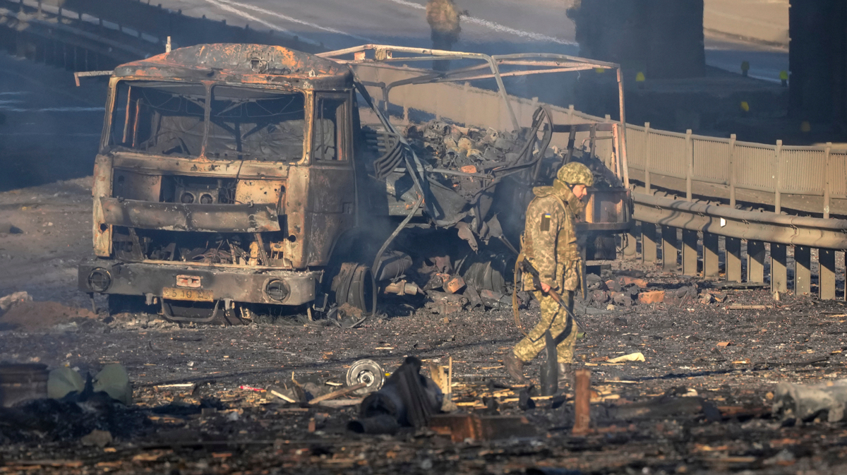Un soldado ucraniano se desplaza entre los restos de un camión militar incendiado en una calle en Kiev, Ucrania, el sábado 26 de febrero de 2022. (AP Foto/Efrem Lukatsky)