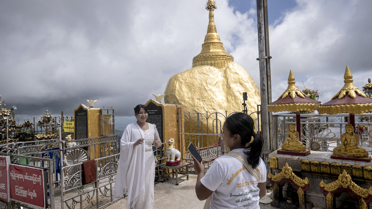 This photo taken on May 28, 2026 shows people posing for photos at the Kyite Htee Yoe Pagoda, also known as the Golden Rock Pagoda, in Mon State. (Sai Aung Main/AFP/Getty Images/TNS)