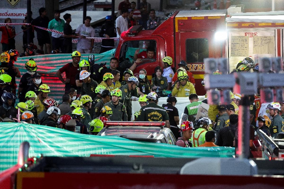 Emergency services members carry a dead body at a site where a train collided with a bus and several cars on Asok-Din Daeng Road, causing several casualties, in Bangkok, Thailand, May 16, 2026. REUTERS/Athit Perawongmetha