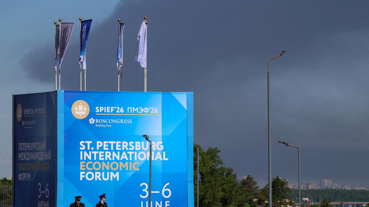 Police officers stand in front of a banner and flags with the logo of the St. Petersburg International Economic Forum as heavy smoke billows in the background after Ukrainian drones hit infrastructure, according to Governor Alexander Beglov, in St Petersburg, Russia, on Wednesday.