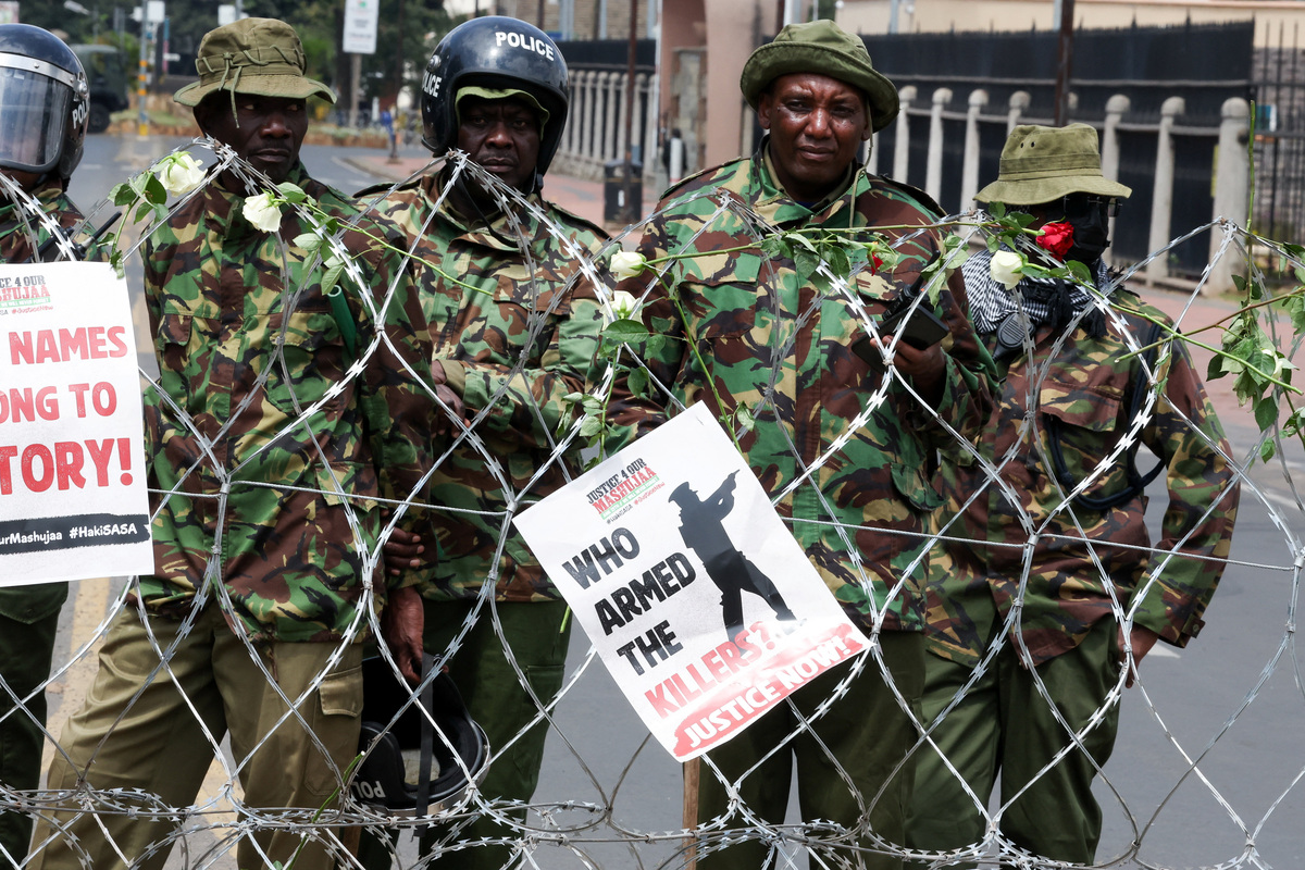 Police officers stand guard, next to flowers and placards placed by protesters on razor wire, during demonstrations to mark the second anniversary of the deadly 2024 anti-government protests, in Nairobi, Kenya, June 25, 2026. REUTERS/Monicah Mwangi