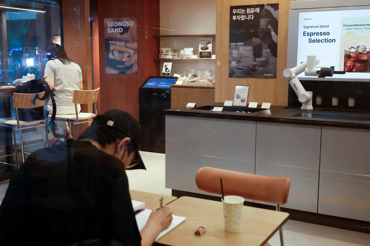 People sit inside an unmanned cafe where a robot arm prepares coffee in Seoul, South Korea, June 19, 2026. REUTERS/Kim Soo-hyeon