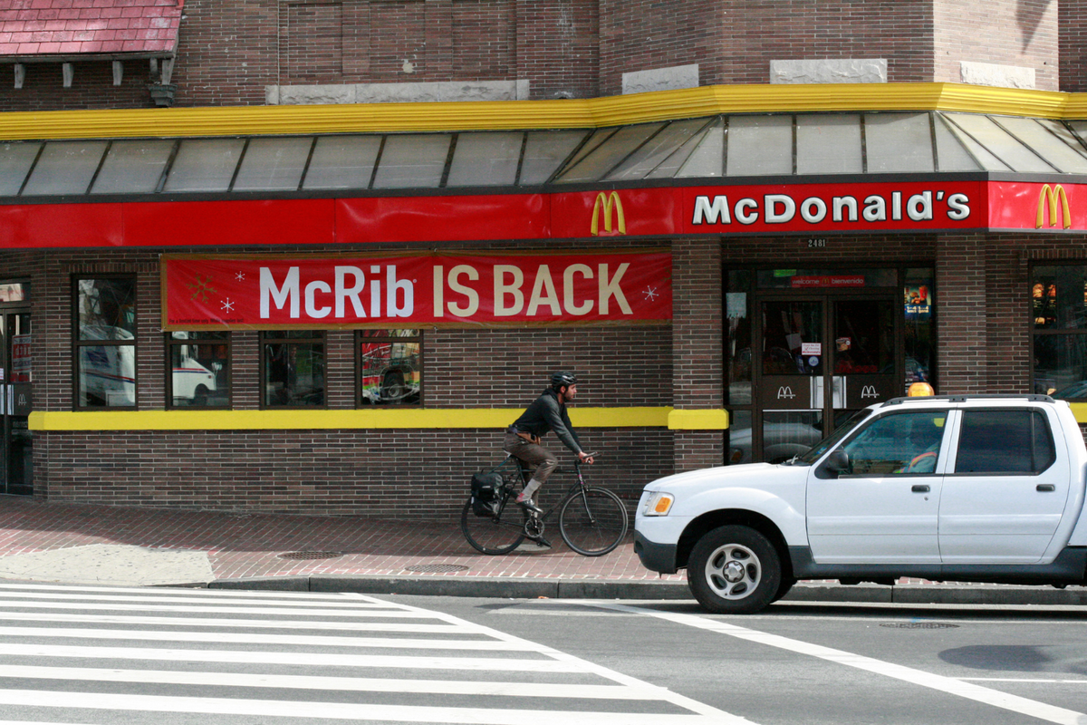 A man bicycles past a McDonald’s restaurant on November 2, 2010, in Washington, featuring a sign announcing the return of the McRib. 