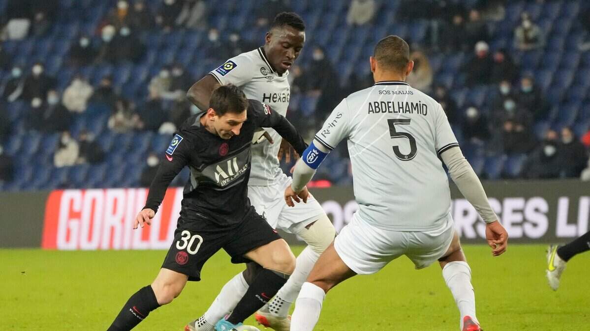 El delantero argentino del Paris Saint-Germain Lionel Messi trata de pasar la defensa de dos jugadores de Reims, en el partido de la liga francesa celebrado el 23 de enero de 2022.