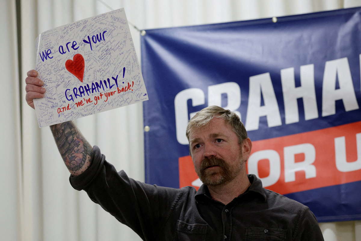 FILE PHOTO: Democratic candidate for U.S. Senate Graham Platner holds up a handmade card given to him by an audience member reading 'We Are your Grahamily And We've Got Your Back!' during a campaign town hall meeting in Portland, Maine, U.S., June 7, 2026. REUTERS/Brian Snyder/File Photo