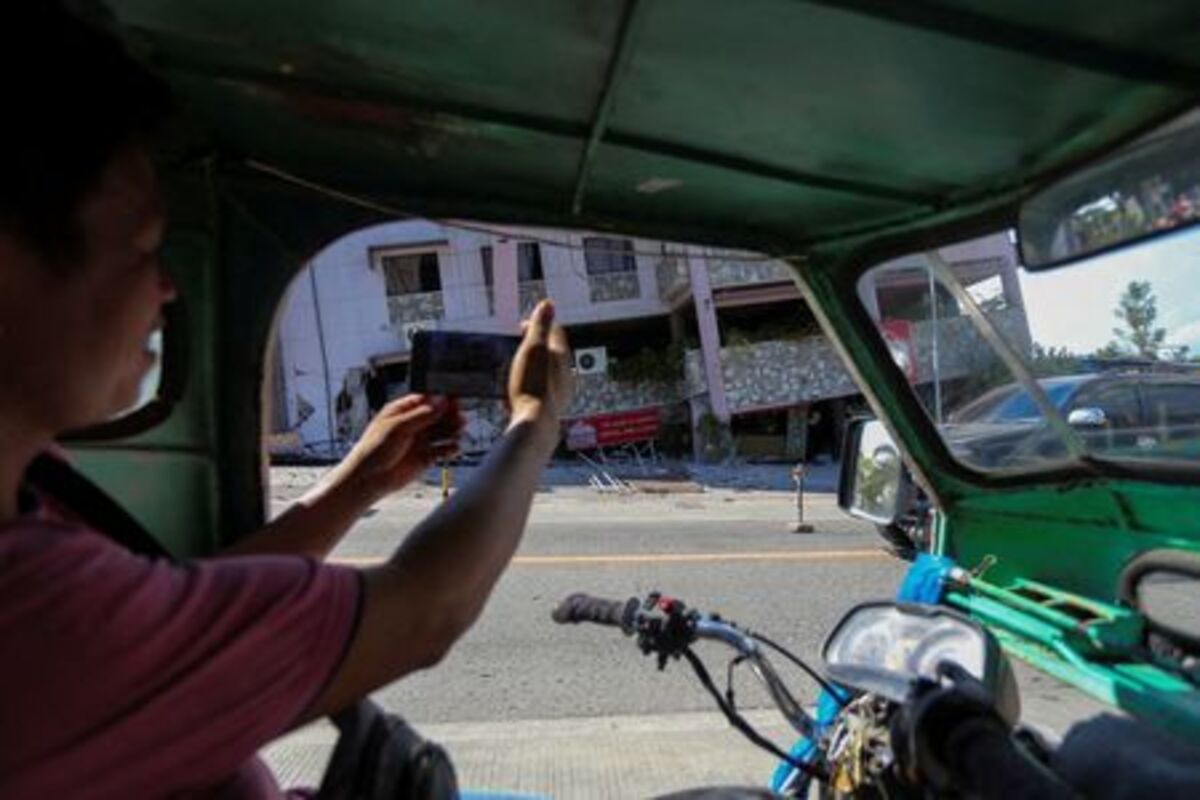 A man takes a photo of a damaged building following the magnitude 7.8 quake in General Santos, southern Philippines, June 8, 2026. REUTERS/Manman Dejeto
