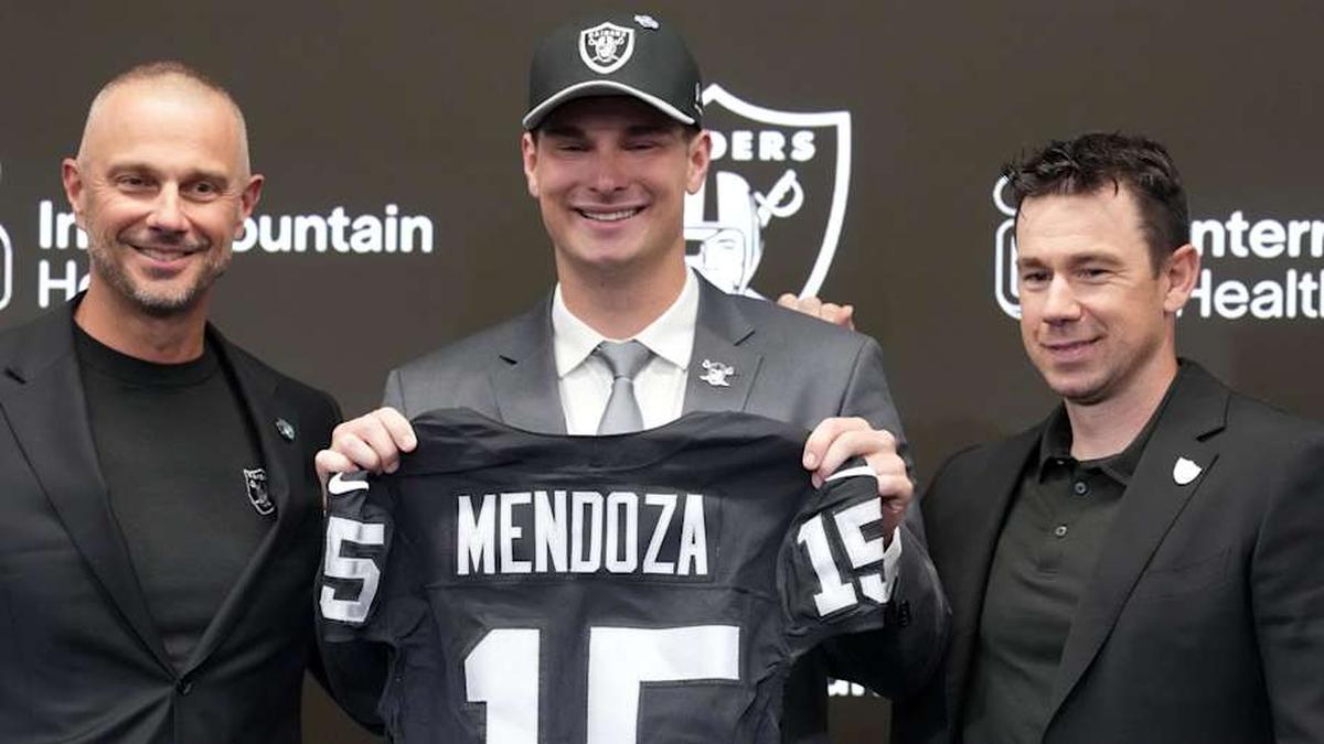  Apr 24, 2026; Henderson, NV, USA; Las Vegas Raiders quarterback Fernando Mendoza (center) poses with jersey at introductory press conference at Intermountain Health Performance Center flanked by general manager John Spytek (left) and head coach Klint Kubiak after being selected as the No. 1 pick in the 2026 NFL Draft. Mandatory Credit: Kirby Lee-Imagn Images | Kirby Lee-Imagn Images 