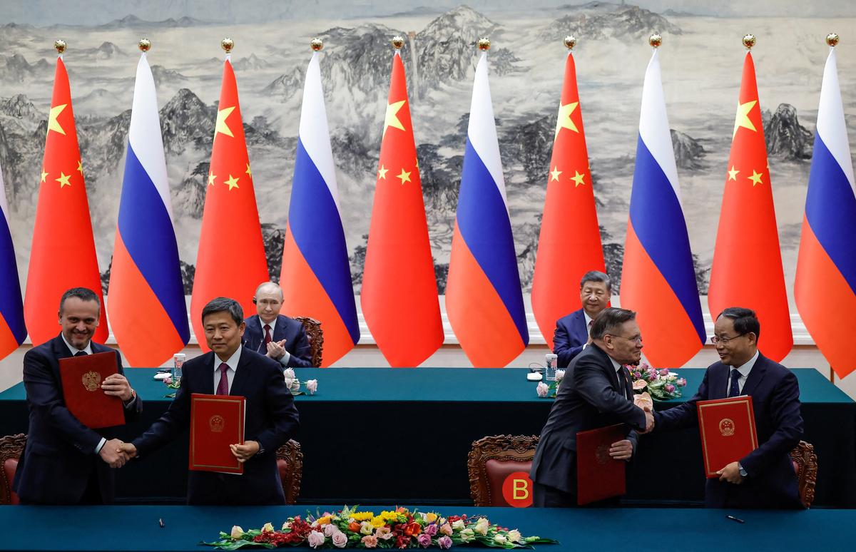 Russian President Vladimir Putin and Chinese President Xi Jinping look on as officials exchange with agreement folders during a signing ceremony at the Great Hall of the People in Beijing, China May 20, 2026. REUTERS/Maxim Shemetov/Pool