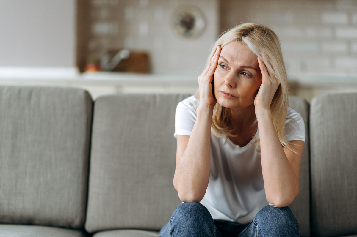  Stock image: a woman looks unhappy with her head in her hands. 