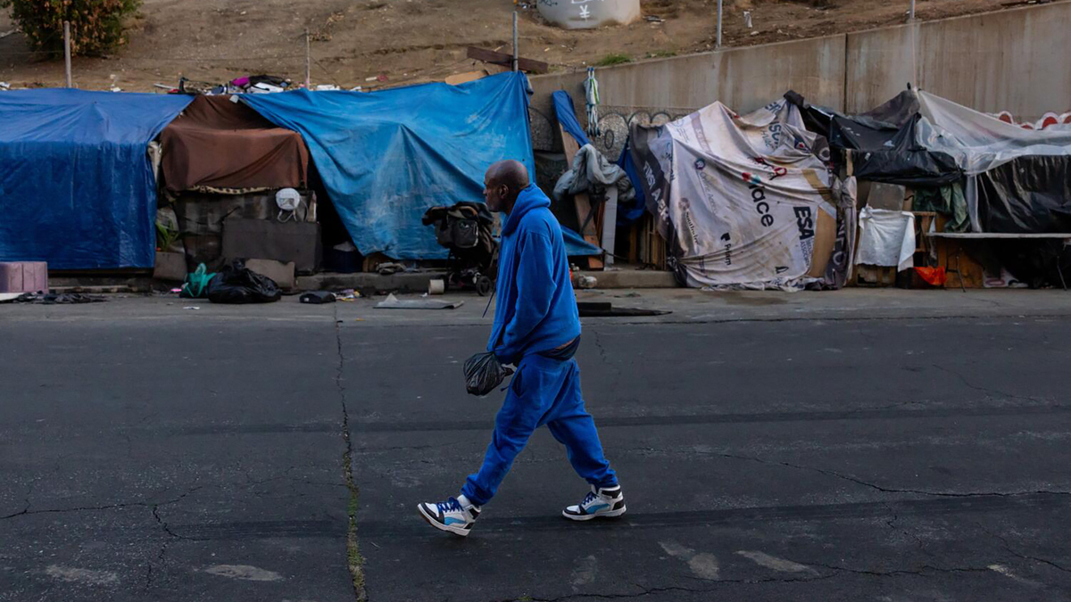 A man walks by a homeless encampment in downtown Los Angeles as a federal judge has found that the city violated the constitutional rights of homeless people in hundreds of cleanups that were not adequately documented to ensure personal property was not seized and destroyed, on Feb. 12, 2026. (Jason Armond/Los Angeles Times/TNS)