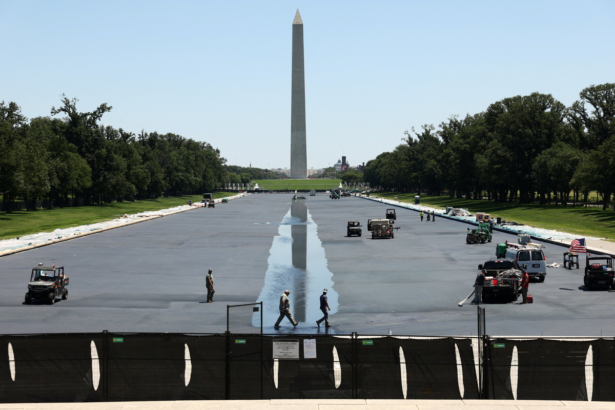 Workers walk along the Reflecting Pool as it is refilled with water after being painted blue at the direction of U.S. President Donald Trump ahead of America 250, in Washington, D.C., U.S., June 4, 2026. REUTERS/Kevin Lamarque