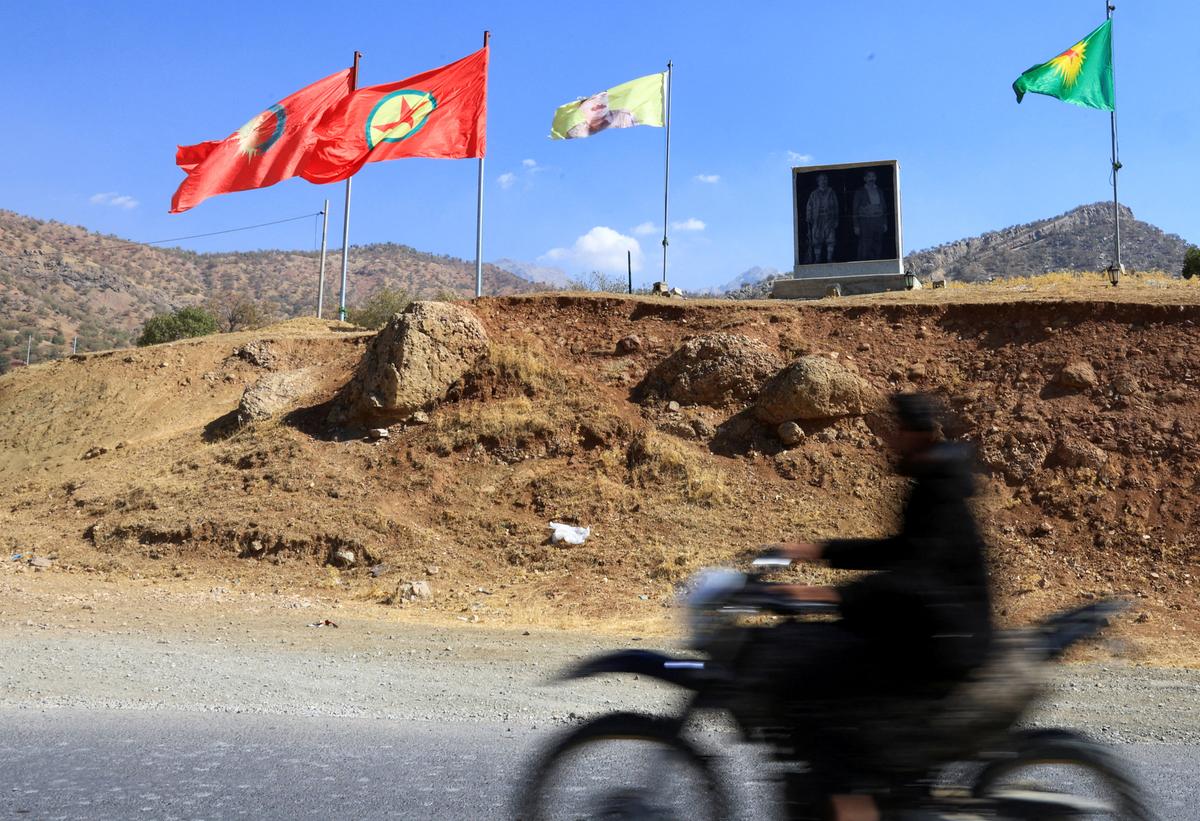 FILE PHOTO: A fighter with the Kurdistan Workers' Party (PKK) rides a motorcycle past flags in the Qandil mountains, Iraq, October 26, 2025. REUTERS/Thaier Al-Sudani/File Photo