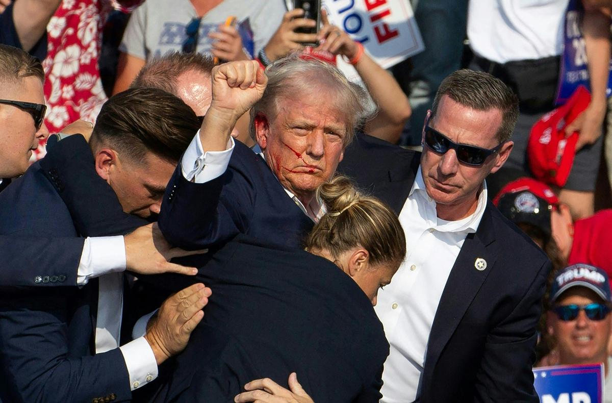  Then-Republican presidential candidate Donald Trump is seen with blood on his face surrounded by Secret Service agents as he is taken off the stage after being grazed by a bullet at a campaign event in Butler, Pennsylvania, on July 13, 2024. 