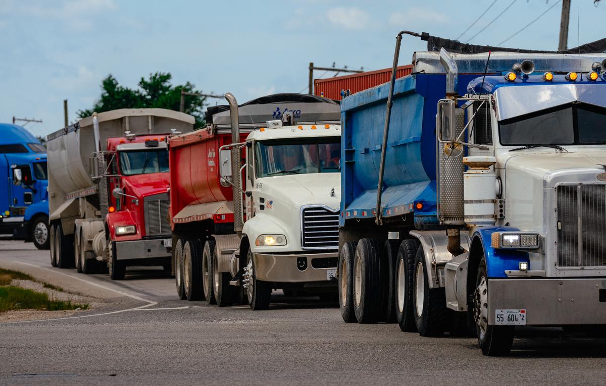 Trucks line up at a busy intersection after departing from several distribution centers, including an Amazon cross-dock facility, in Joliet, Ill. on June 30, 2025. 25 years ago, the far outskirts of the Chicago suburbs were mostly farmland. Today, warehouse complexes dominate. With them, the roads have become increasingly dangerous. (Jamie Kelter Davis/The New York Times)....