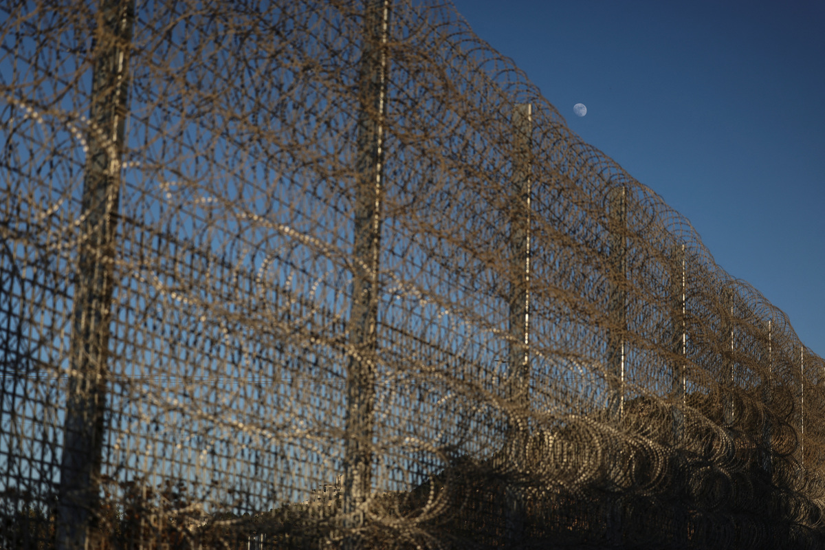The moon above the tall metal fencing installed by the Israeli military that closed off four of the five entrances to Sinjil, near Ramallah, in the Israeli-occupied West Bank, June 26, 2026. REUTERS/Ammar Awad