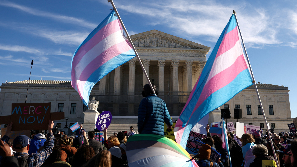 FILE PHOTO: Demonstrators carry a transgender flags outside the U.S. Supreme Court, on the day the justices heard oral arguments in two cases concerning efforts to enforce Republican-backed state laws banning transgender athletes from female sports teams at public schools, in Washington, D.C., U.S., January 13, 2026. REUTERS/Kevin Lamarque/File Photo