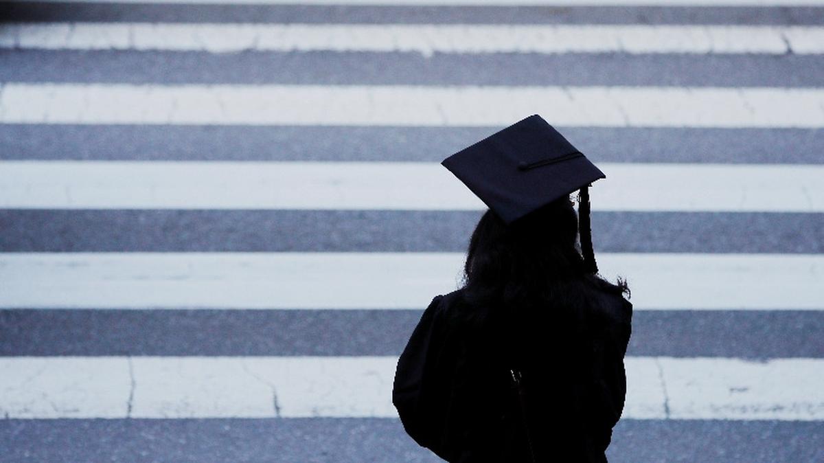 FILE PHOTO: A graduating student waits to cross the street in Cambridge, Massachusetts, U.S., June 7, 2019. REUTERS/Brian Snyder/File Photo