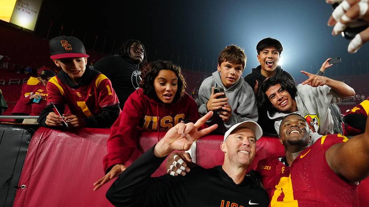  Nov 29, 2025; Los Angeles, California, USA; Southern California Trojans head coach Lincoln Riley (right) and defensive tackle Jahkeem Stewart (4) pose with fans after the game against the UCLA Bruins at United Airlines Field at Los Angeles Memorial Coliseum. Mandatory Credit: Kirby Lee-Imagn Images | Kirby Lee-Imagn Images 