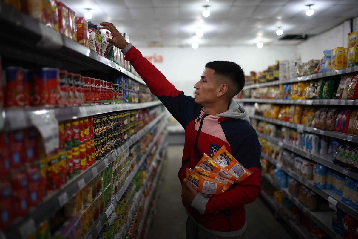 Emiliano Migueles, 26, picks up boxed tomatoes at a supermarket to prepare a weekly dinner with friends in the Parque San Martin neighbourhood in Merlo, on the outskirts of Buenos Aires, Argentina, April 20, 2026. Migueles starts his days early, delivering water. But his true grind begins when he clocks out and hits the scrappy soccer pitches that dot the suburbs of Buenos Aires, pouring his energy into amateur football to earn extra cash. REUTERS/Agustin Marcarian