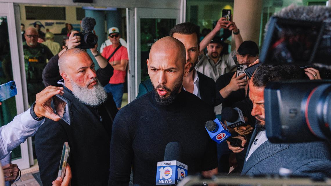 The British American online influencer Andrew Tate speaks to reporters after he and his brother Tristan Tate, obscured at center right, arrived at Fort Lauderdale-Hollywood International Airport in Florida on Thursday, Feb. 27, 2025. The brothers, who had been barred from leaving Romania for more than two years over criminal investigations, were allowed by a judge to leave on Thursday, a development that raised questions about whether the Trump administration played a role in their sudden departure. (James Jackman/The New York Times)
