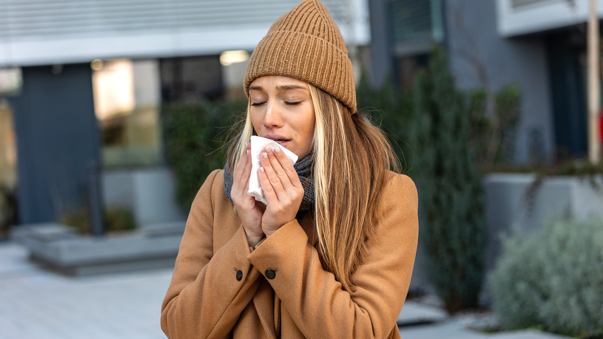 A stock image of a woman blowing her nose. 