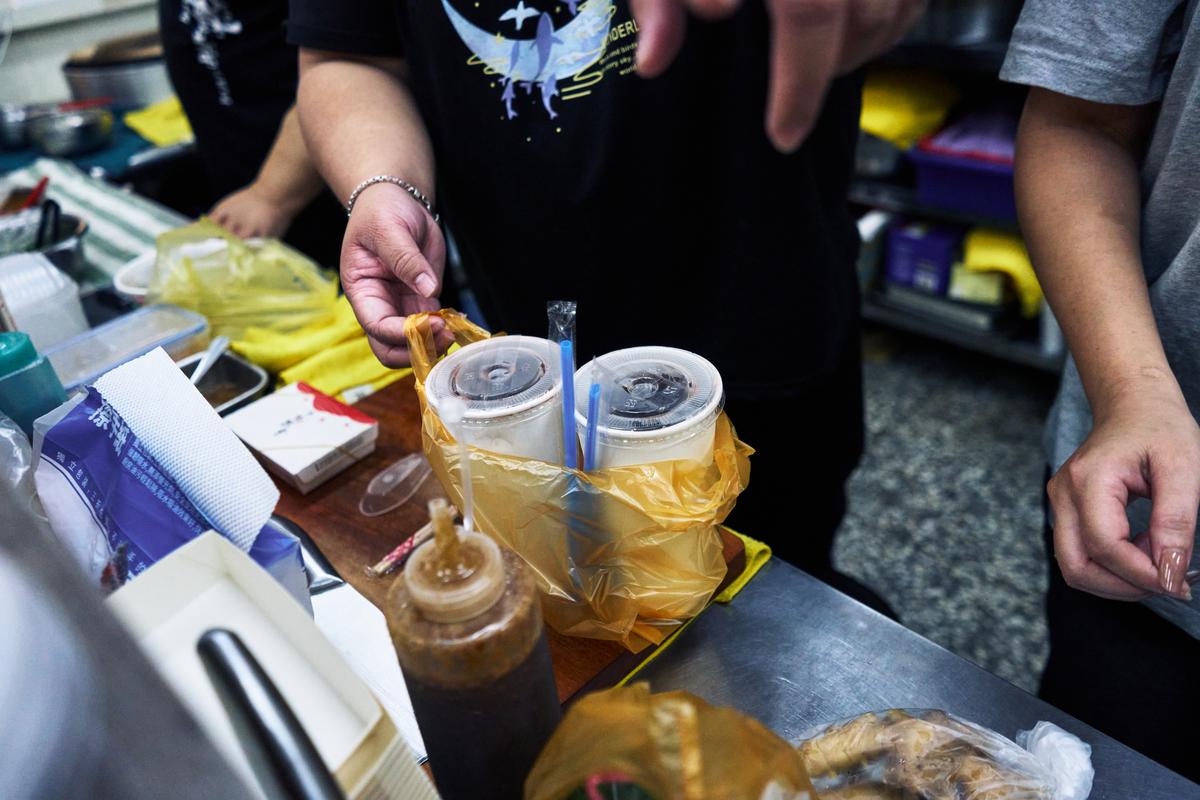 Yeh Pi-chiu, who manages a rice vermicelli noodle shop near the Xizhou Public Market, hands a delivery driver an order in Taipei,Taiwan on April 8, 2026. Plastic producers in Taiwan have scrambled to secure new supplies since the war in Iran disrupted petrochemical flows and tightened availability. (An Rong Xu/The New York Times)
