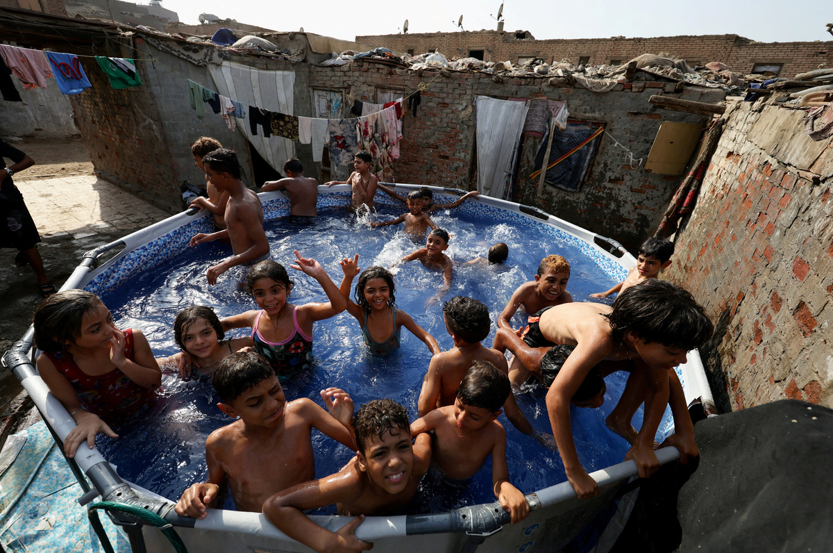 FILE PHOTO: Children play in a portable swimming pool, offering respite from the summer heat for residents who are unable to afford travelling to the beaches along the Mediterranean Sea to cool off, during a heat wave, in Manshiyet Nasser shanty town, Al-Duwayqa, in Cairo, Egypt, August 11, 2025. REUTERS/Mohamed Abd El Ghany/File Photo