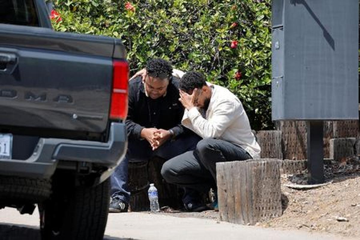 Men console each other as they sit on a sidewalk, near the scene of a reported active shooter situation at the Islamic Center, in San Diego, California, U.S., May 18, 2026.  REUTERS/Mike Blake