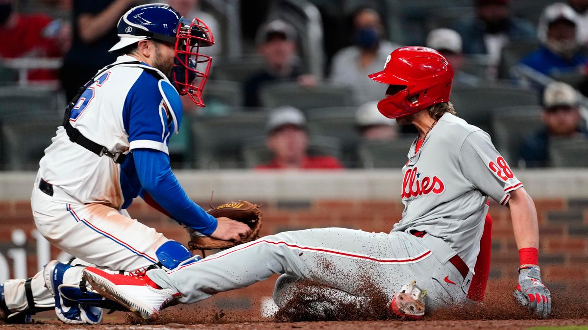 Philadelphia Phillies’ Alec Bohm (28) beats the tag from Atlanta Braves catcher Travis d’Arnaud (16) to score the winning run on a Didi Gregorius sacrifice fly in the ninth inning of a baseball game Sunday, April 11, 2021, in Atlanta. (AP Photo/John Bazemore)