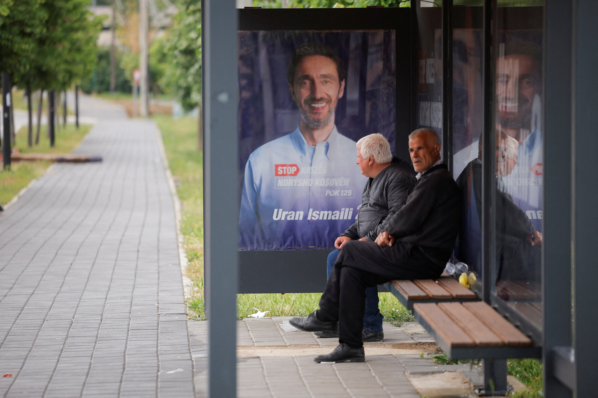 People wait at a bus station near the election posters of the Democratic Party of Kosovo (PDK) in Pristina, Kosovo, June 4, 2026. Kosovo is to hold a snap parliamentary election, the third in just over a year, after parliament failed to elect a new head of state. REUTERS/Valdrin Xhemaj