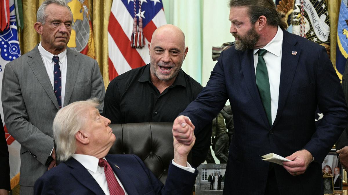 U.S. Secretary of Health and Human Services Robert F. Kennedy Jr., top left, and media personality Joe Rogan, middle, look on as U.S. President Donald Trump, bottom left, shakes hands with W. Bryan Hubbard, CEO of Americans for Ibogaine, during an executive order signing ceremony in the Oval Office of the White House in Washington, D.C., on Saturday, April 18, 2026. (Jim Watson/AFP/Getty Images/TNS)