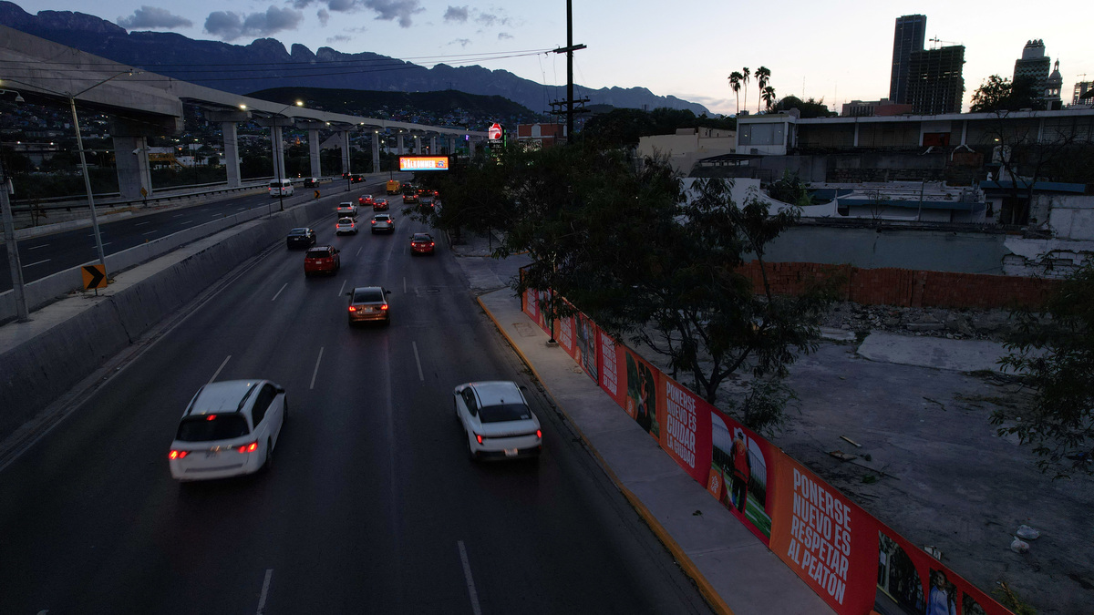 A drone view shows vehicles driving by a fence bearing advertising from the Nuevo Leon state government, erected by authorities along a road to the stadium and airport to block poorer neighbourhoods from view, as many Mexicans say they feel excluded despite the tournament's return to the country, citing high ticket prices, paid television access and strict commercial restrictions, in Monterrey, Mexico, June 12, 2026. REUTERS/Daniel Becerril