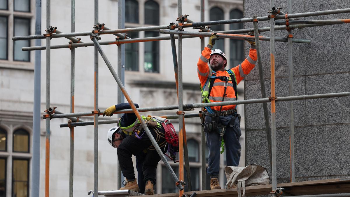 Construction workers work on a scaffolding at an office building, in London, Britain, January 16, 2025. REUTERS/Isabel Infantes