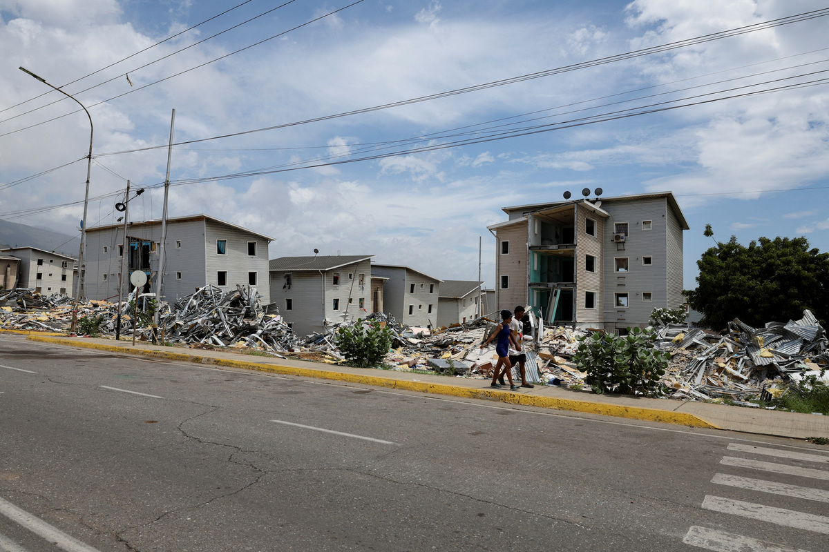 People walk on a street by piles of debris in the aftermath of the June 24 earthquakes, in La Guaira, Venezuela, July 6, 2026. REUTERS/Ricardo Arduengo