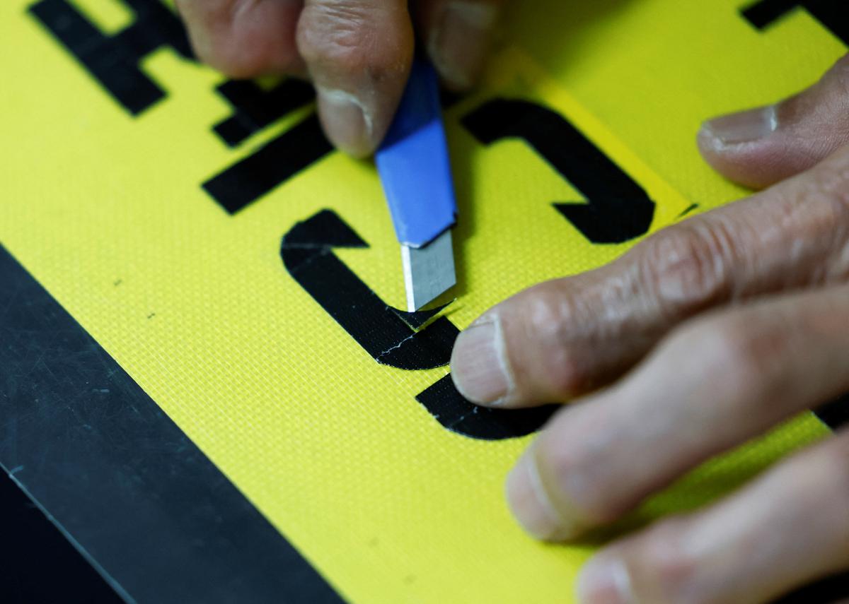 Shuetsu Sato, a security guard whose handmade duct-tape signs have gained widespread recognition, makes a duct-tape sign at a security company office where he works, in Tokyo, Japan, May 1, 2026.  REUTERS/Kim Kyung-Hoon
