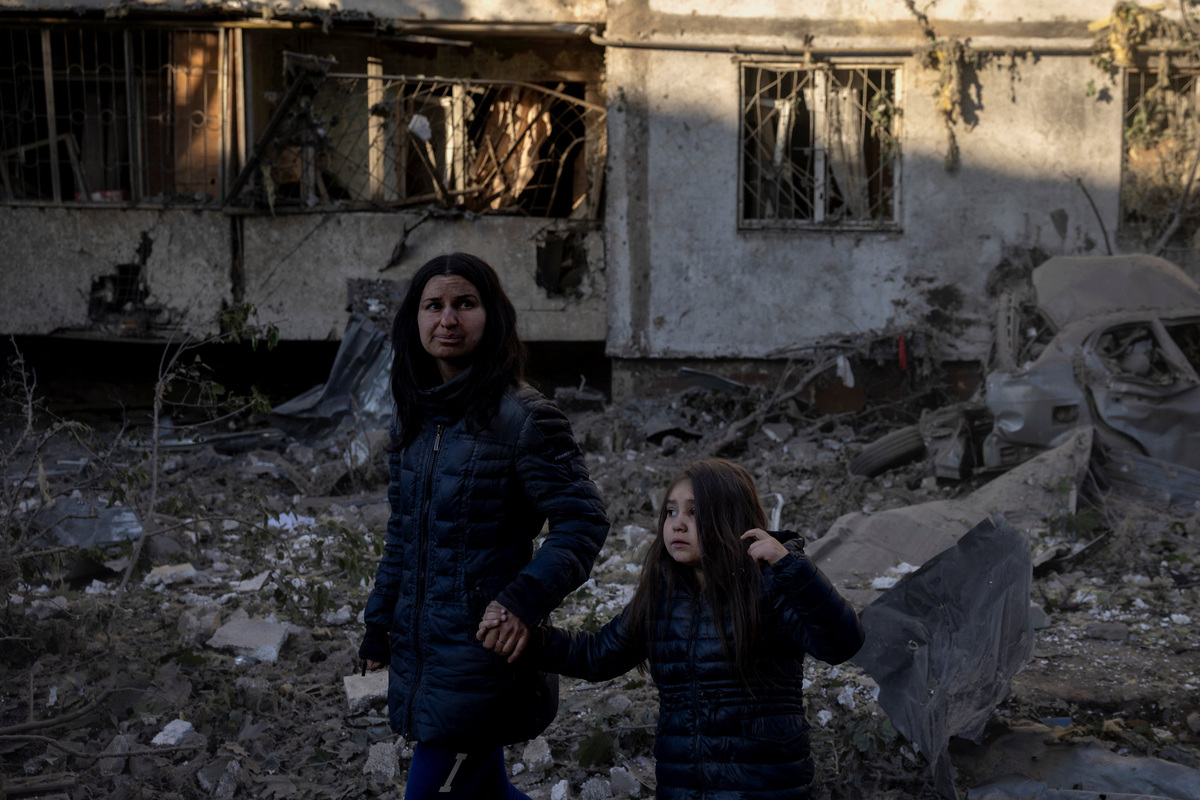 Olha Mudra, 35, and her six-year-old daughter, Nataliia, walk past their damaged apartment building in Kyiv, covered in dust after surviving a nearby strike, amid Russia's attack on Ukraine, in Kyiv, Ukraine, June 2, 2026. REUTERS/Thomas Peter