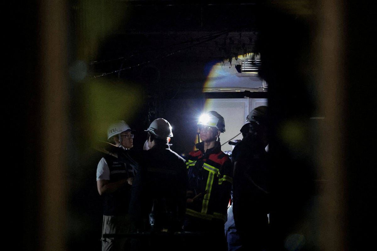 A firefighter wears a helmet with a torch, at the site of a deadly fire at a pub in Bangkok, Thailand, July 13, 2026. REUTERS/Chalinee Thirasupa