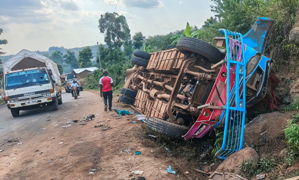 Vehicles drive past the wreckage of a bus, owned by King David Junior School, on the shoulder of the road following an accident that killed schoolchildren on the way back from an educational visit to Sipi Falls; at Chekwatit village in Kapchorwa district, Uganda, July 17, 2026. Picture taken with a mobile phone. REUTERS/Stringer
