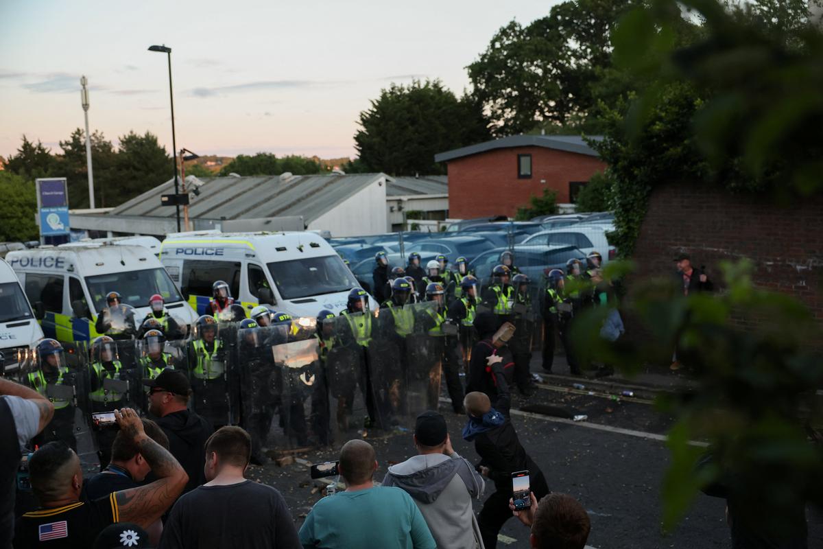 Police officers stand guard as a protester throws a brick toward them during a demonstration following the conviction of Vikrum Digwa for the murder of student Henry Nowak, in Southampton, Britain, June 2, 2026. REUTERS/Isabel Infantes