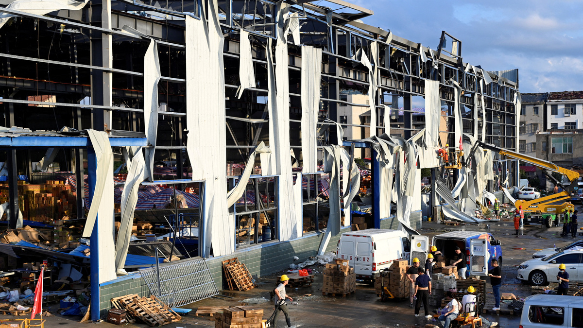 Rescue workers carry out repair work as volunteers and staff members transfer supplies at a logistics park struck by a tornado the night before, in Huangzhou district of Huanggang, Hubei province, China July 7, 2026. China Daily via REUTERS
