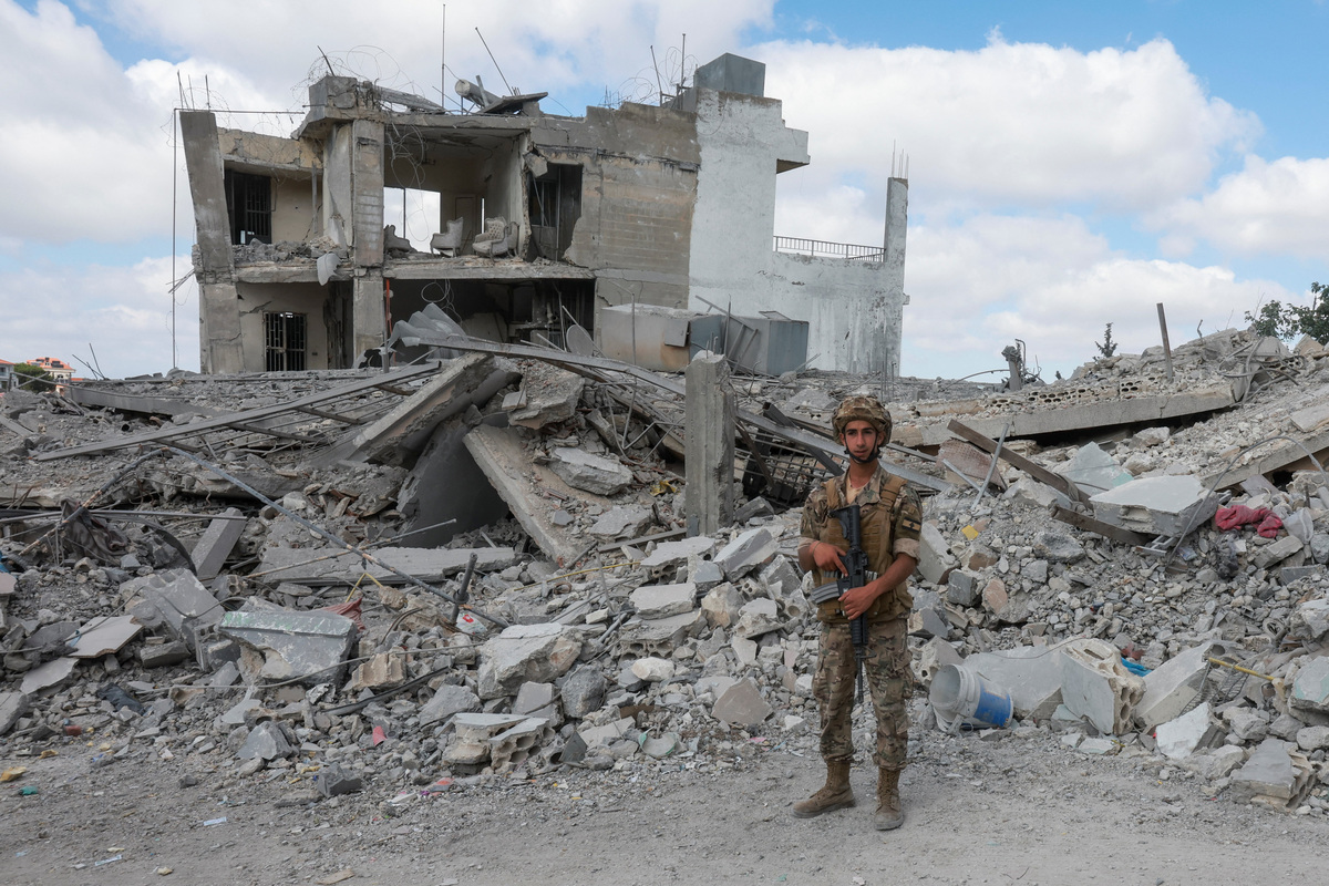 A members of the Lebanese army stands guard near rubble of destroyed buildings, as people make their way back to their homes, following a peace deal between the United States and Iran, in Bir Al-Salasil, Tyre district, southern Lebanon, June 15, 2026. REUTERS/Aziz Taher