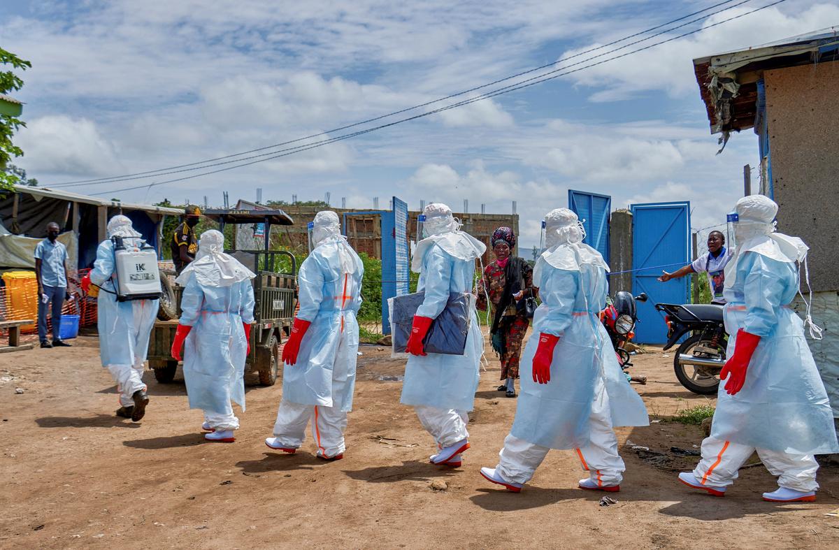 People react while Red Cross workers walk in a formation as they disinfect Rwampara general hospital before handling the body of a person who died of Ebola, as aid agencies intensify efforts to contain a new Ebola outbreak involving the Bundibugyo strain, in Rwampara outside Bunia, Ituri province, Democratic Republic of Congo, May 21, 2026. REUTERS/Gradel Muyisa Mumbere