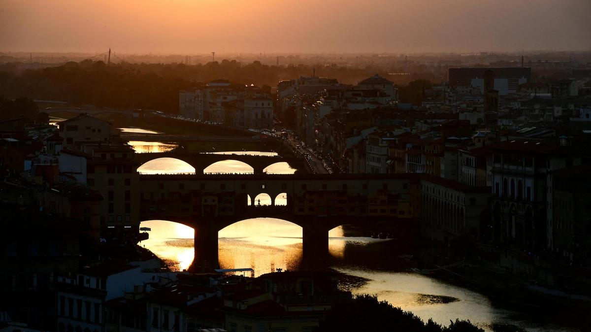 A picture taken on June 13, 2019 shows the sunset over the "Ponte Vecchio" (Old Bridge) on the Arno river in Florence, Tuscany. (Photo by Miguel MEDINA / AFP)