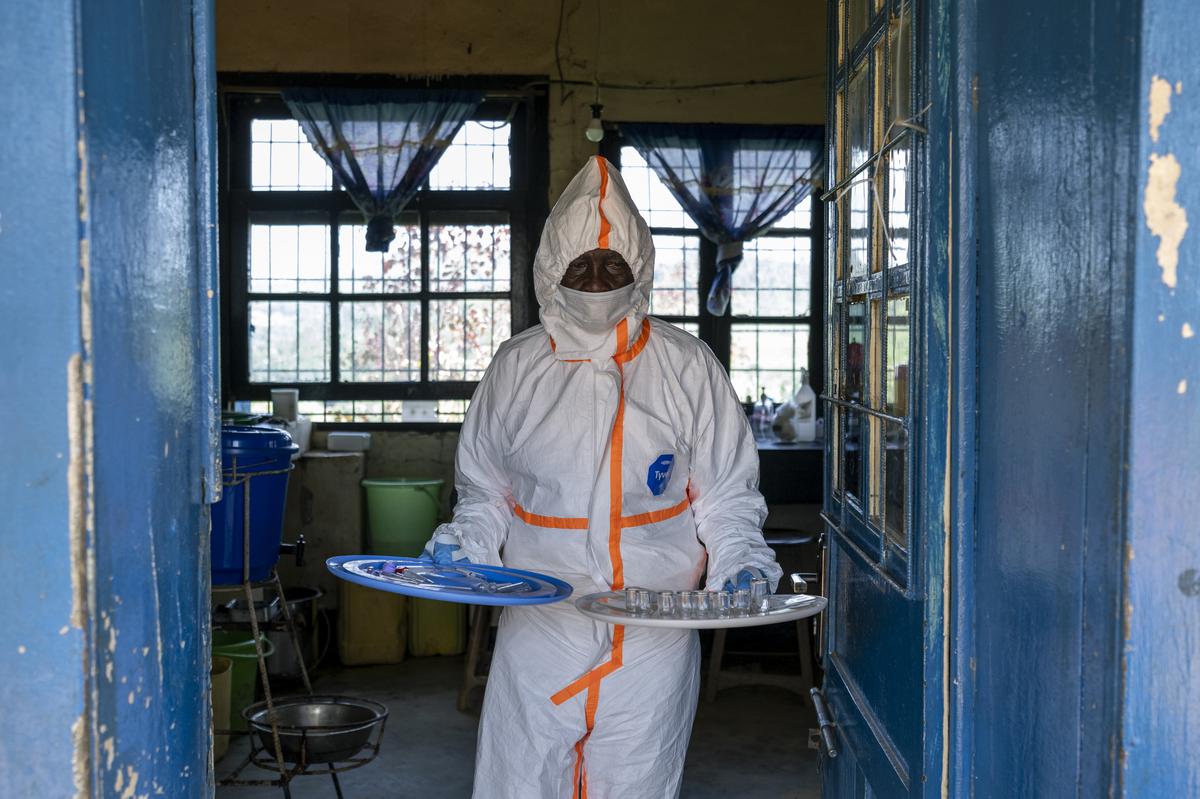 Ferdinand Kaso Lots', a laboratory hygienist, takes lab supplies out into the sun for reuse at the general hospital, in the mining town of Mongbwalu, which is at the epicenter of the Ebola virus outbreak in Democratic Republic of Congo, May 27, 2026. In a remote gold mining town at the epicenter of the Ebola outbreak, medical workers struggle to beat back a surge of deaths and infections. (Arlette Bashizi/The New York Times)