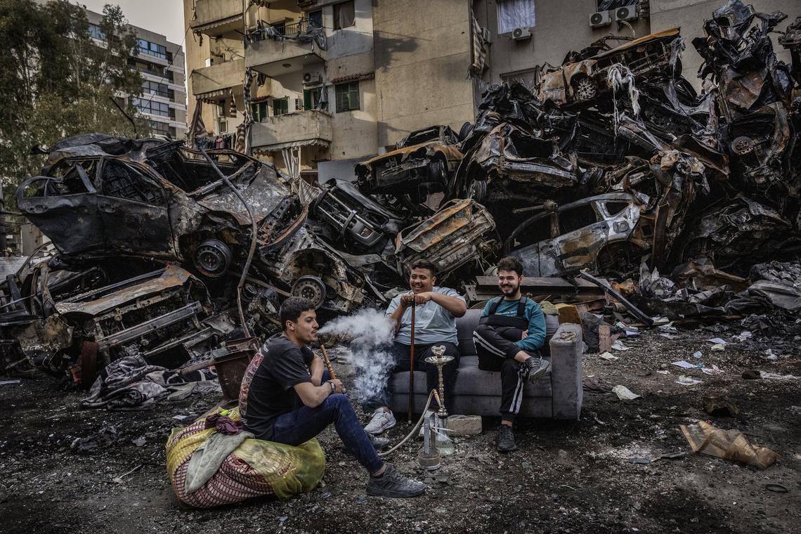 Residents sit near a pile of burned vehicles in the rubble left by Israeli bombardment in Beirut, Lebanon, April 14, 2026. President Donald Trump announced on Thursday that the leaders of Israel and Lebanon have agreed to a 10-day cease-fire, a development that could bring an end to fighting between Israel and the Iranian-backed militant group, Hezbollah. (David Guttenfelder/The New York Times)
