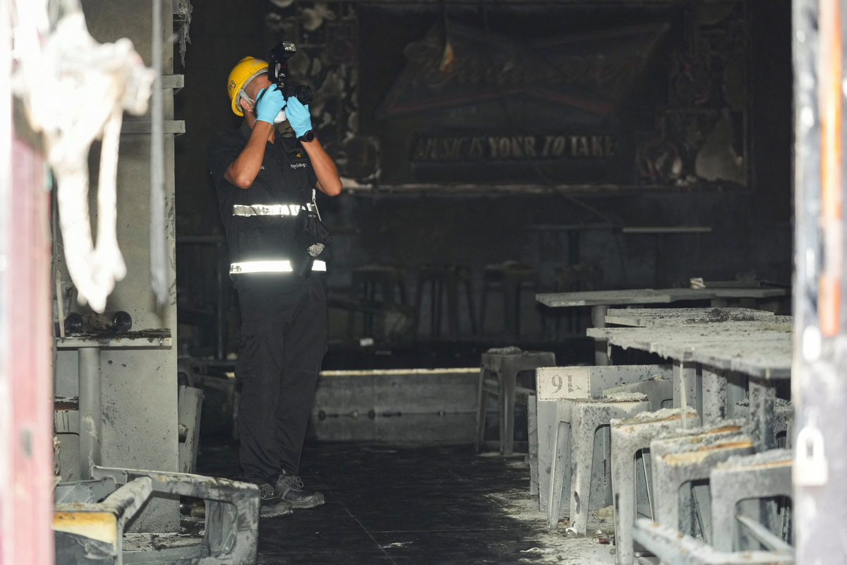 A forensic police official takes photographs the site of a deadly fire at a pub in Bangkok, Thailand, July 13, 2026. REUTERS/Arnun Chonmahatrakool