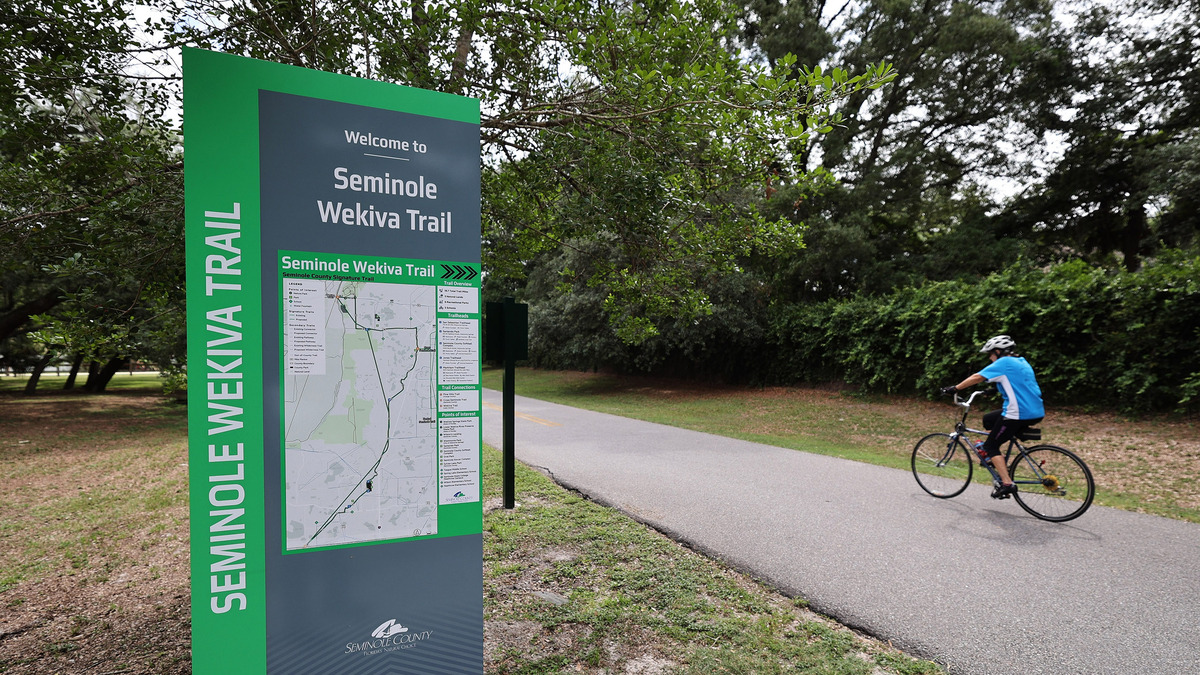 A cyclist goes past the sign for the Jones Trailhead of the Seminole Wekiva Trail in Longwood, Florida, on June 10, 2026. (Ricardo Ramirez Buxeda/Orlando Sentinel/TNS)