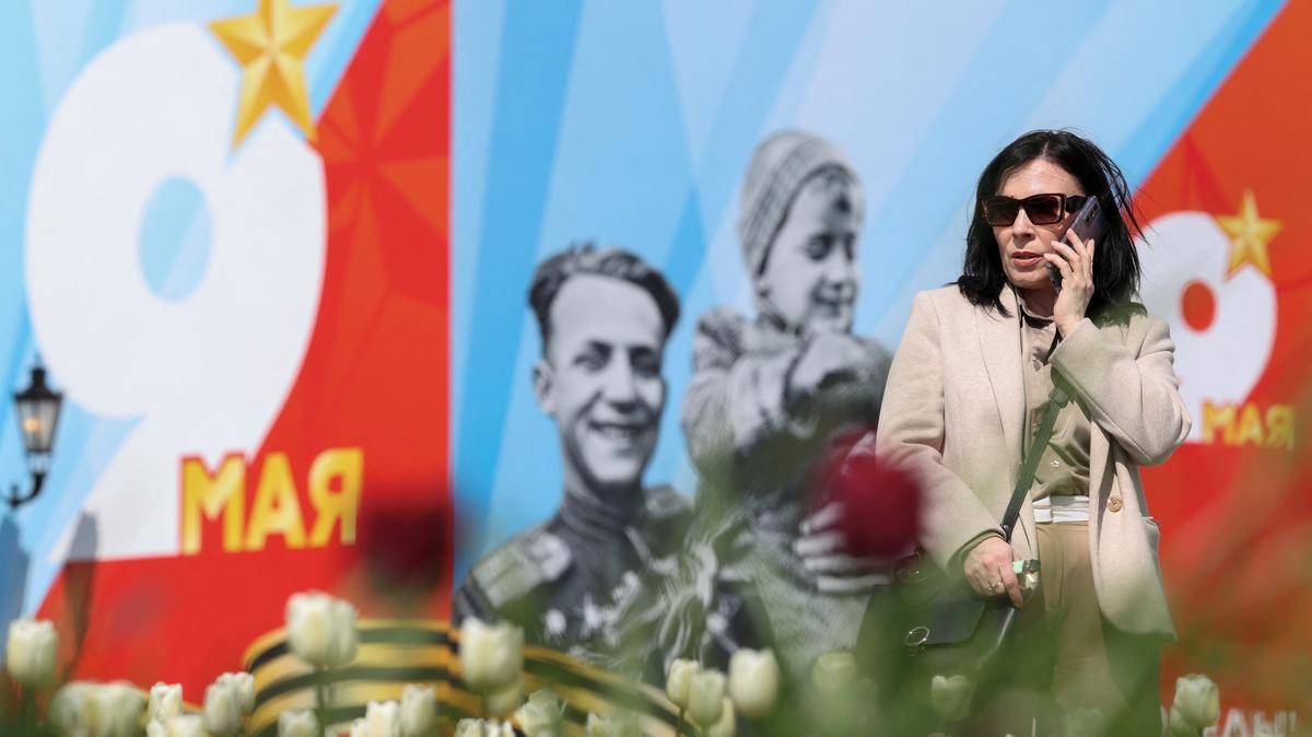 A woman talks on the phone in front of a banner for the Victory Day military parade, marking the anniversary of victory over Nazi Germany in World War Two, in central Moscow, Russia, May 4, 2026. REUTERS/Ramil Sitdikov